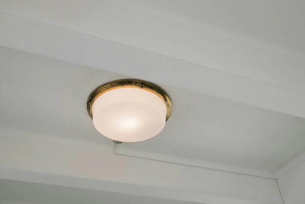 Round flush mount ceiling light with a brass trim ring on a white ceiling